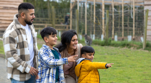A wide shot of a family of four walking through various enclosures together at a zoo in Northumberland